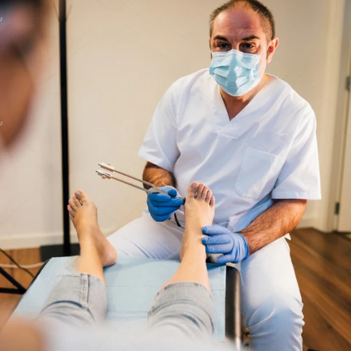 Médecin qui utilise un diapason thérapeutique sur le pied d'une patiente.
